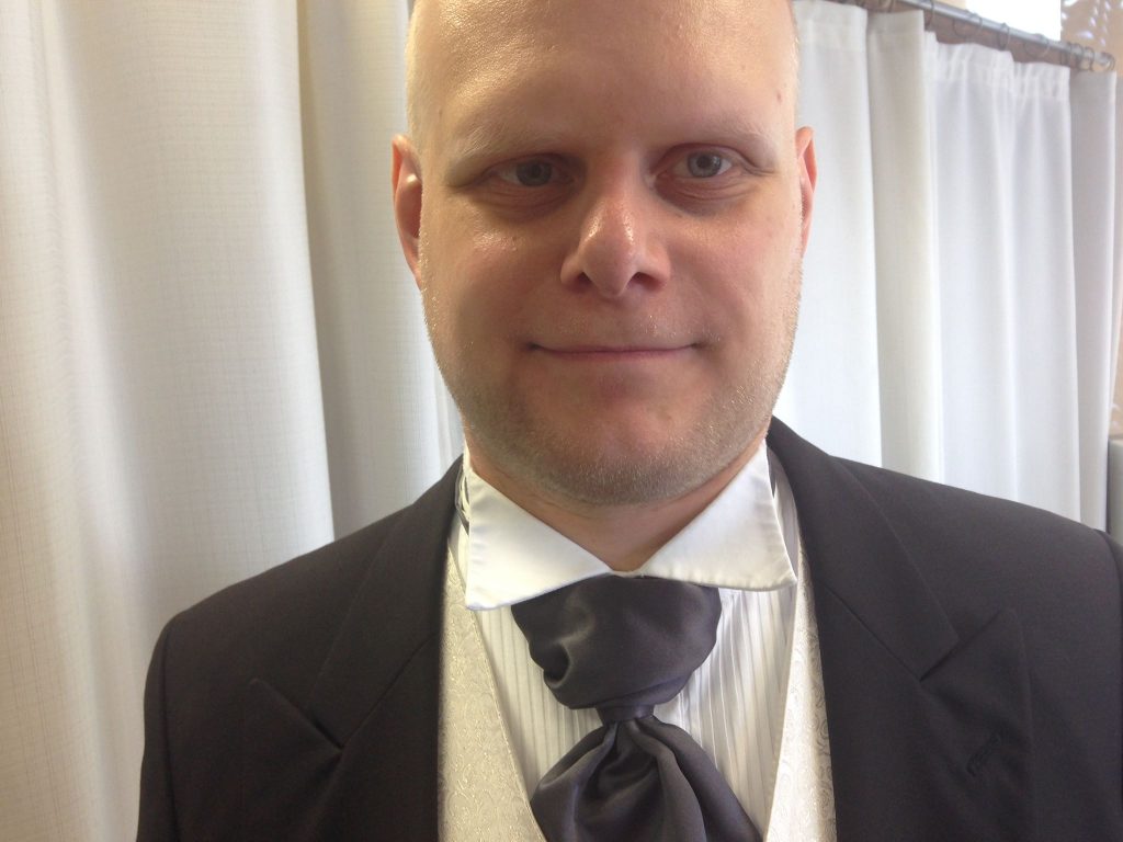 Kuvassa on Anssi, josta näkyy pää ja saketin takin yläosa, kauluspaita ja solmio.