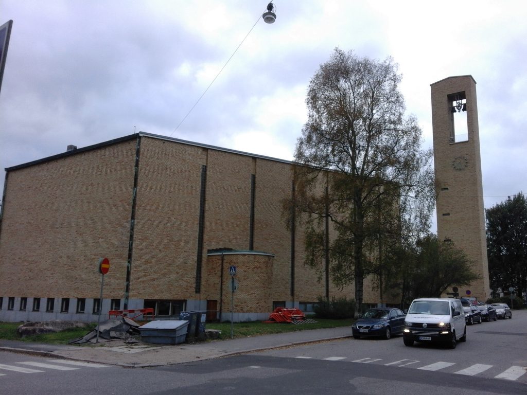 Kuvassa on Helsingin Meilahden kirkko Mannerheimintien suunnasta nähtynä. Keltatiilisessä kirkossa näkyy kirkkorakennus sekä kellotapuli.